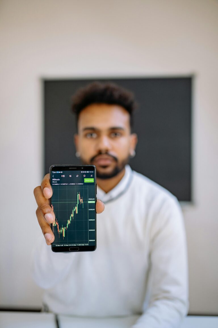 Man holding smartphone with stock market chart, focusing on financial growth.